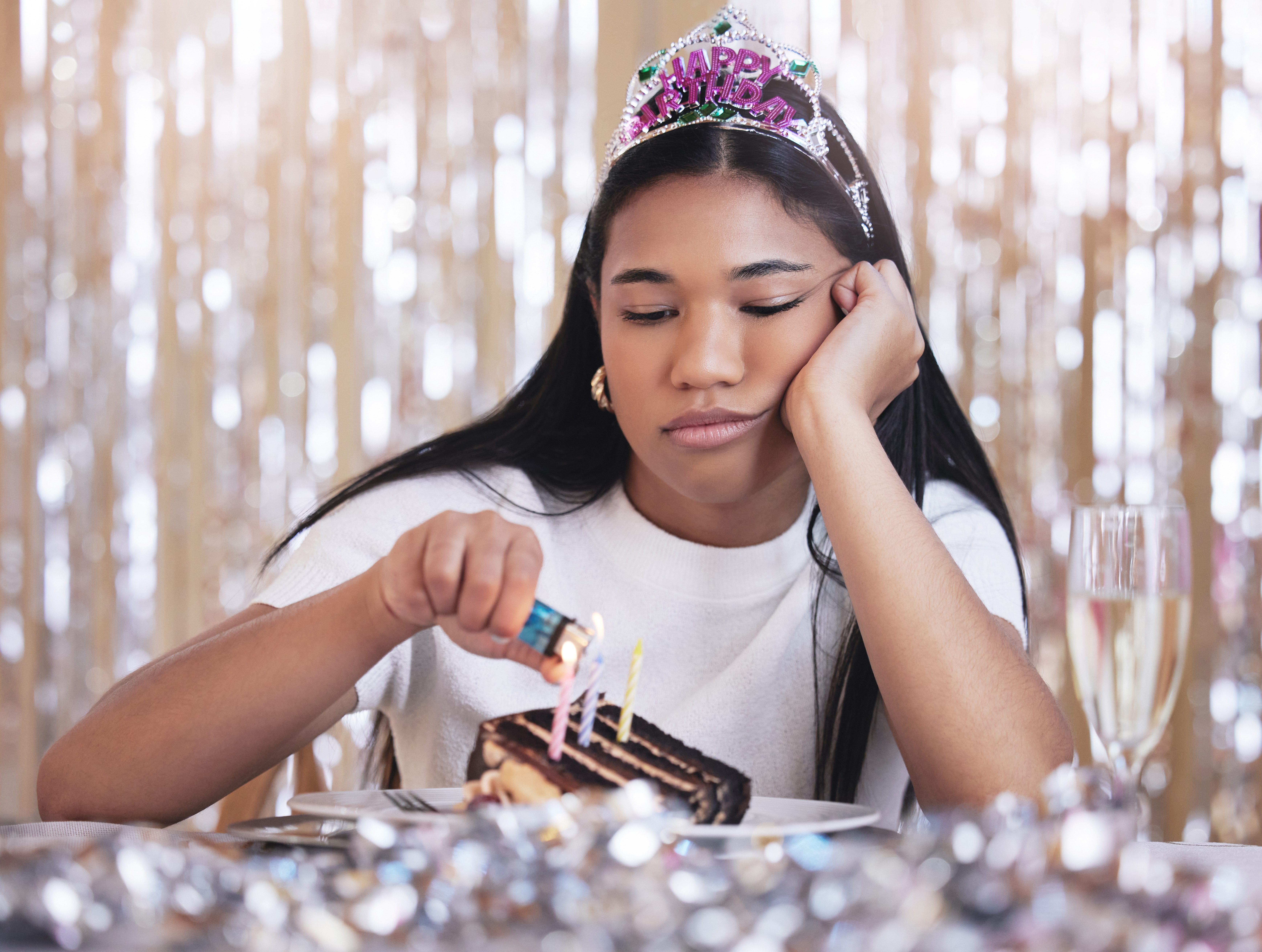 Sad, depression and angry woman at birthday celebration while lighting candle on cake. Lonely, depr
